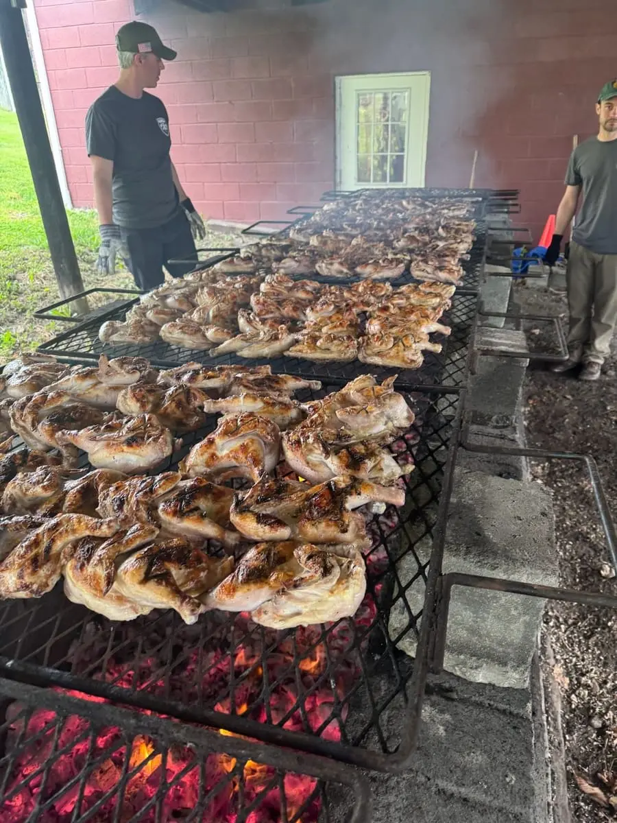 Rows of chicken halves grilling over charcoal at the Ghent Volunteer Fire Company Chicken BBQ fundraiser