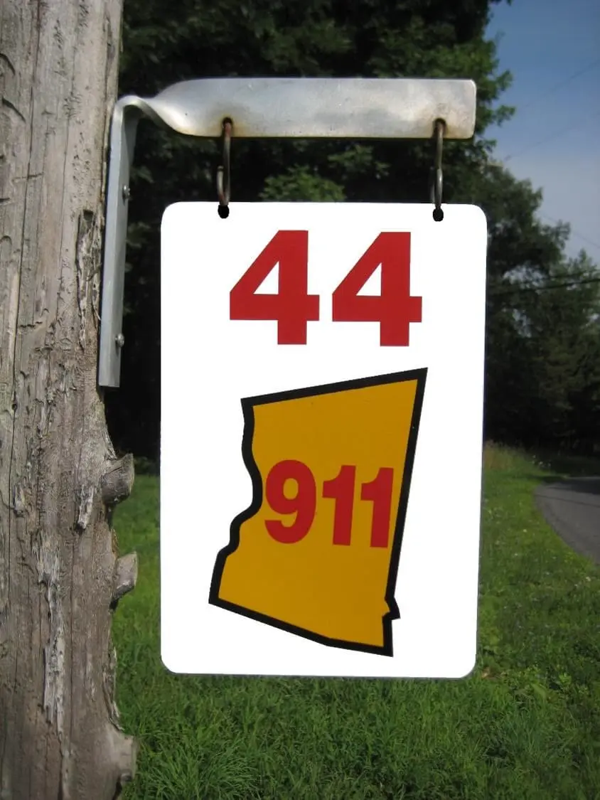 Reflective 911 emergency address sign mounted on a wooden mailbox post in Ghent